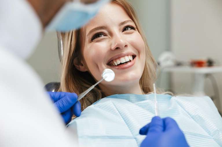 Smiling woman relaxes in dentist chair, awaiting emergency crown appointment with a positive attitud