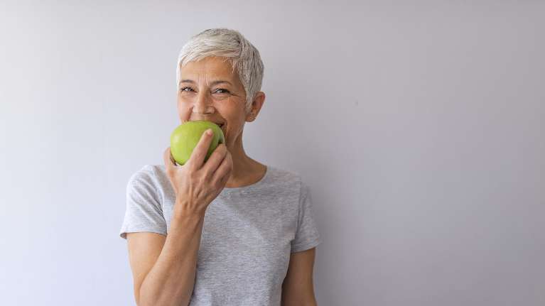 Short haired woman eating green apple in Armidale NSW 