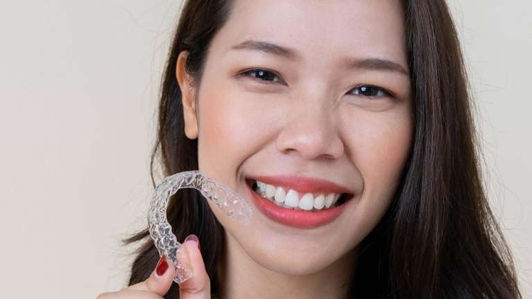 A woman smiling with her clear aligners