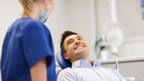 Smiling male patient consulting with dentist about filling costs and treatment options