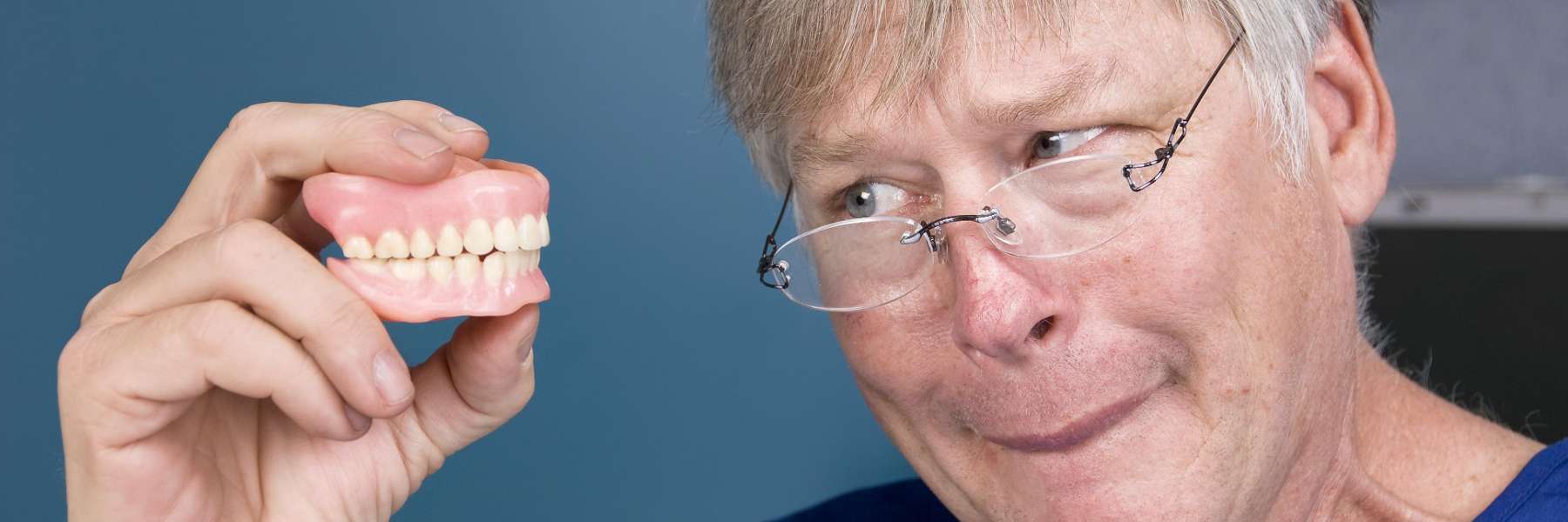 Man holding his pair of dentures in Armidale NSW